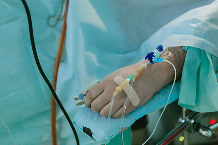 Close-up of a patient’s hand with an IV drip in a medical setting, highlighting care in an apartment environment. Close-up of a patient’s hand with an IV drip in a medical setting, highlighting care in an apartment environment.