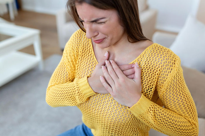 Woman in yellow sweater holding chest in discomfort, illustrating possible side effects of Ozempic diet medicine. Woman in yellow sweater holding chest in discomfort, illustrating possible side effects of Ozempic diet medicine.