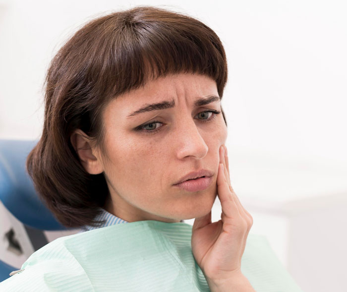 Worried woman touching her cheek sitting in a dental chair, representing concerns about Ozempic diet medicine side effects. Worried woman touching her cheek sitting in a dental chair, representing concerns about Ozempic diet medicine side effects.