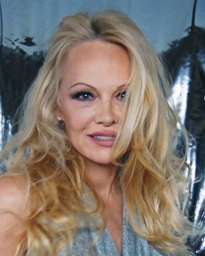 Pamela Anderson showcasing 90s glam makeup with voluminous blonde hair and bold eye makeup in a glamorous setting Pamela Anderson showcasing 90s glam makeup with voluminous blonde hair and bold eye makeup in a glamorous setting