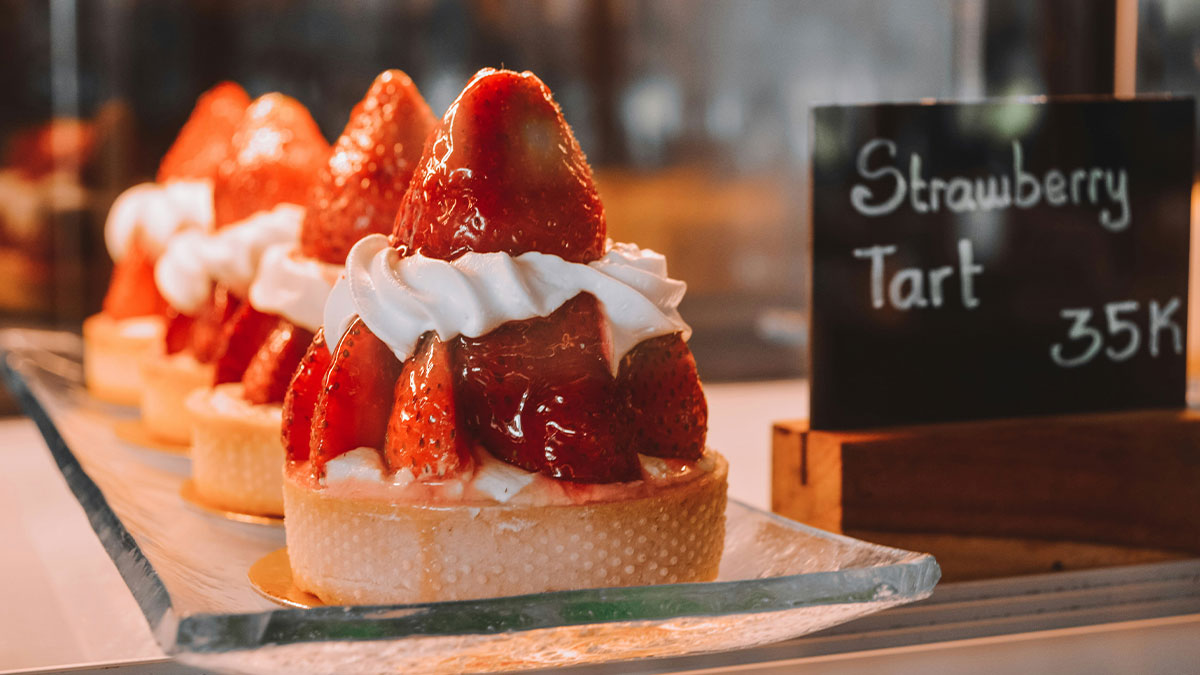 Strawberry tart desserts with whipped cream on display, highlighting partner upset over strawberry allergy concerns.