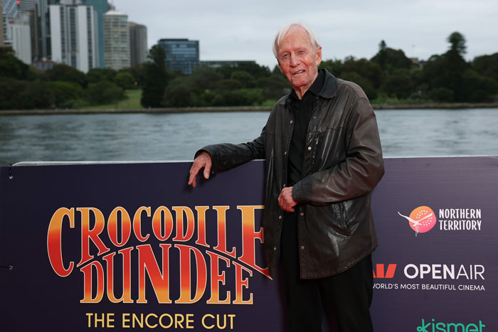 Paul Hogan, legendary Crocodile Dundee star, posing outdoors by a Crocodile Dundee movie sign. Paul Hogan, legendary Crocodile Dundee star, posing outdoors by a Crocodile Dundee movie sign.