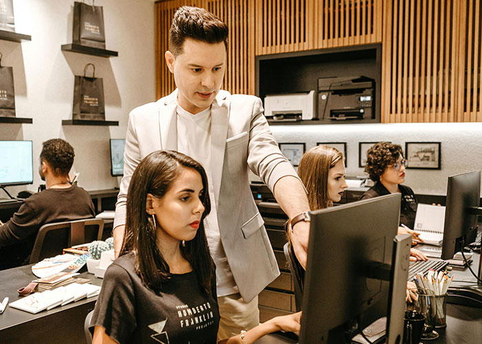 Boss telling workers their pay is late while showing off his new truck in a modern office setting with employees at computers Boss telling workers their pay is late while showing off his new truck in a modern office setting with employees at computers