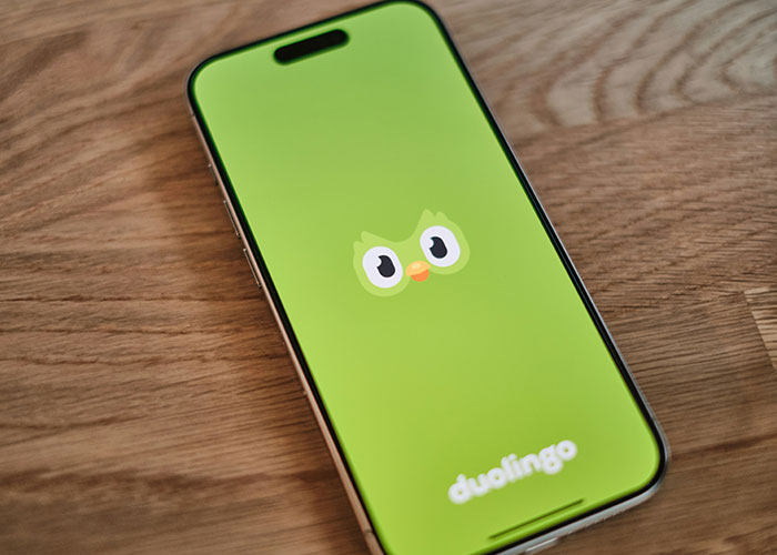 Smartphone displaying Duolingo app with green owl logo, highlighting Duolingo AI-first strategy impacting user experience. Smartphone displaying Duolingo app with green owl logo, highlighting Duolingo AI-first strategy impacting user experience.