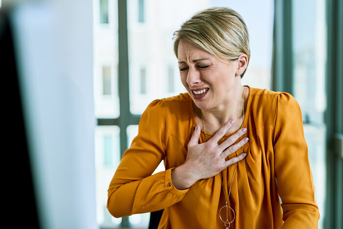 Woman clutching her chest in distress, illustrating spooky tales of people passing away but being resurrected.