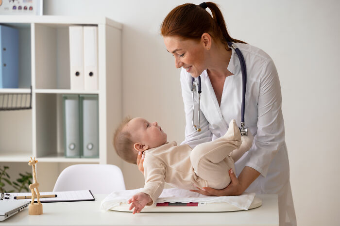 Doctor with stethoscope gently examining baby on table, illustrating spooky tales of people passing away and being resurrected.