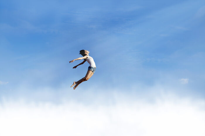Woman in casual clothes appearing to float in the sky against clouds, illustrating spooky tales of passing away and resurrection.