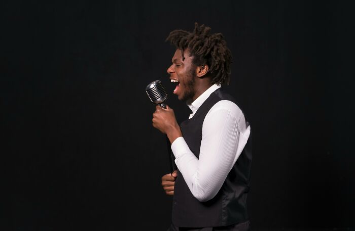 Man passionately singing into vintage microphone, showcasing talent in songs you’ve definitely heard before challenge. Man passionately singing into vintage microphone, showcasing talent in songs you’ve definitely heard before challenge.