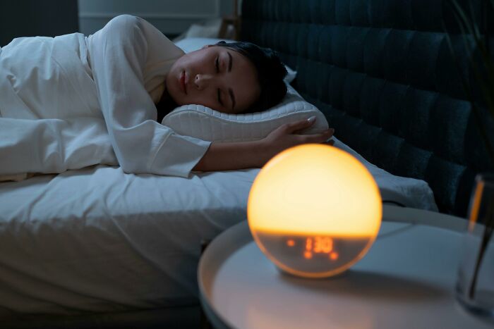 Person sleeping peacefully in bed beside a glowing alarm clock, a tiny thing that made the trip better.