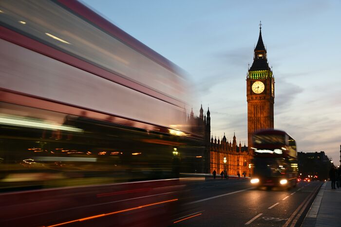 Big Ben clock tower at dusk with iconic red double-decker buses in motion, a famous thing linked to the country quiz. Big Ben clock tower at dusk with iconic red double-decker buses in motion, a famous thing linked to the country quiz.