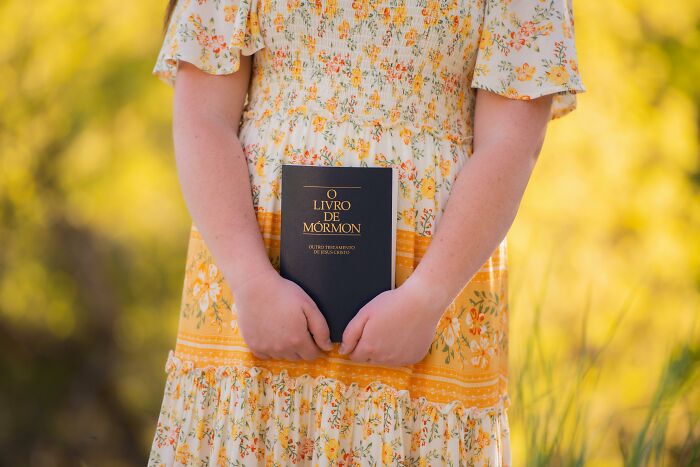 Person in a floral dress holding a book in an outdoor setting illustrating mind-boggling beliefs some smart people embrace.