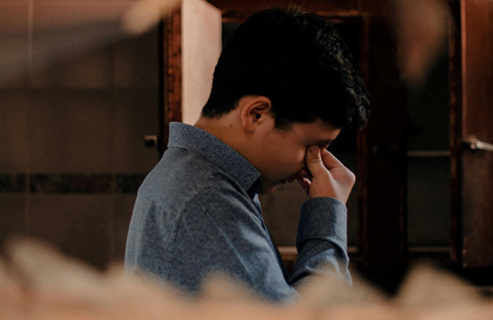 Man in blue shirt showing emotional distress, reflecting on grandbaby as a sign from late wife in a dimly lit room. Man in blue shirt showing emotional distress, reflecting on grandbaby as a sign from late wife in a dimly lit room.