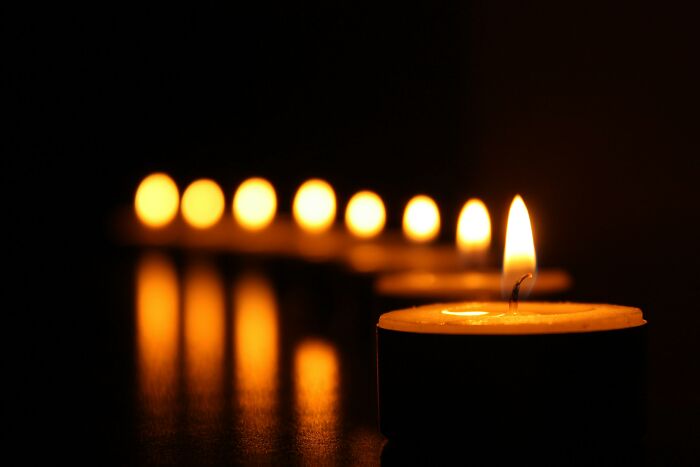 Row of burning candles in the dark symbolizing reflection on morally questionable actions online by netizens including piracy.