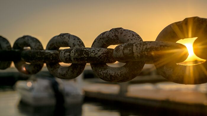 Close-up of a rusty metal chain with sunlight shining through, illustrating the concept of word chains and pattern spotting. Close-up of a rusty metal chain with sunlight shining through, illustrating the concept of word chains and pattern spotting.