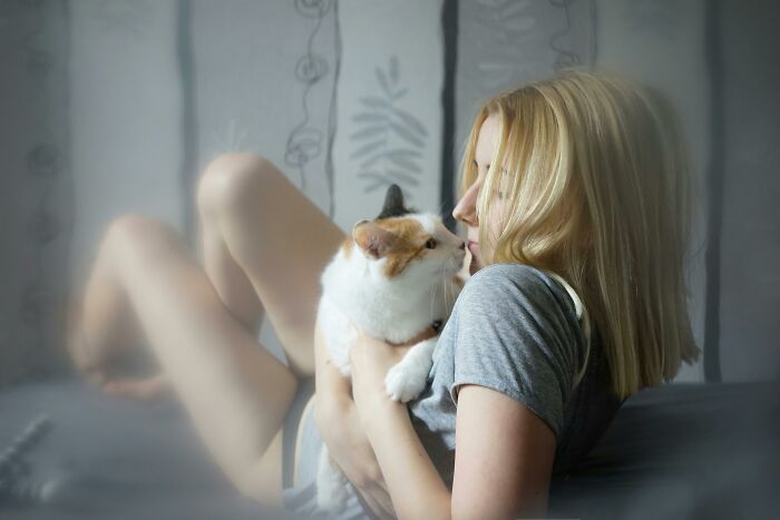Woman enjoying low-key pleasures while holding and cuddling a cat in a cozy, relaxed home setting