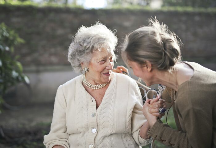 Elderly woman and younger woman laughing together outdoors, reflecting on absurd things people were told growing up.