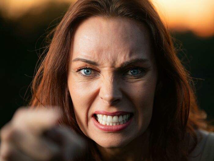 Angry woman with blue eyes and red hair confronting camera, illustrating absurd things people were told growing up.