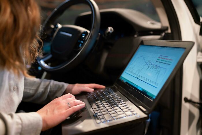 Tech guy analyzing computer data inside a car, uncovering weird or disturbing findings while fixing customer systems.