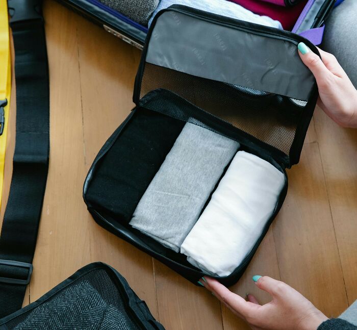 Packing neatly organized rolled clothes in a small travel organizer, showing a tiny thing made trip better for efficient packing.