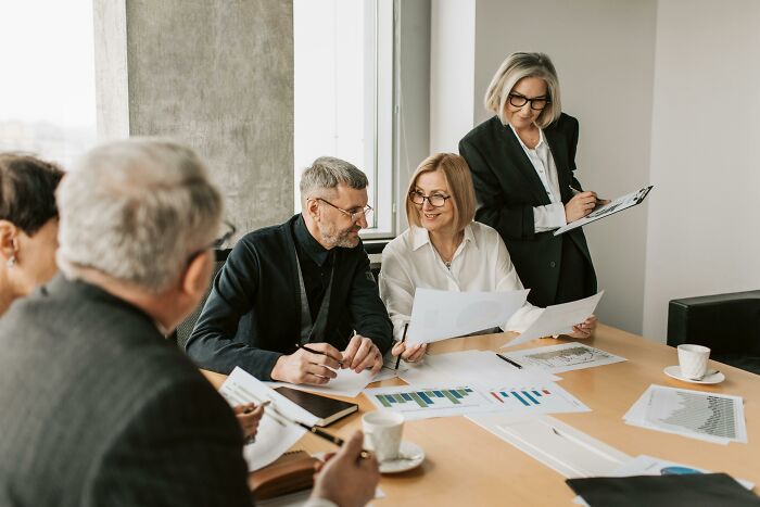Group of professionals discussing documents and charts in a modern office, illustrating absurd things people were told growing up.