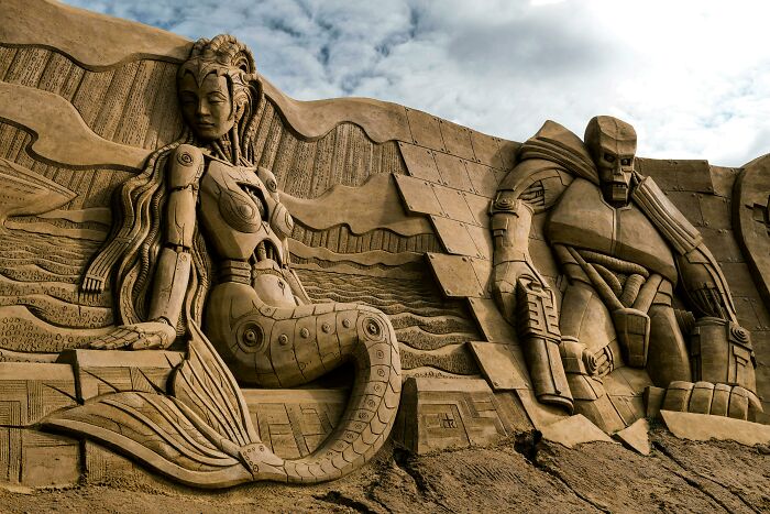 Sand sculptures of mythical creatures including a mermaid and a mechanical golem under a cloudy sky for a mythical creatures quiz. Sand sculptures of mythical creatures including a mermaid and a mechanical golem under a cloudy sky for a mythical creatures quiz.