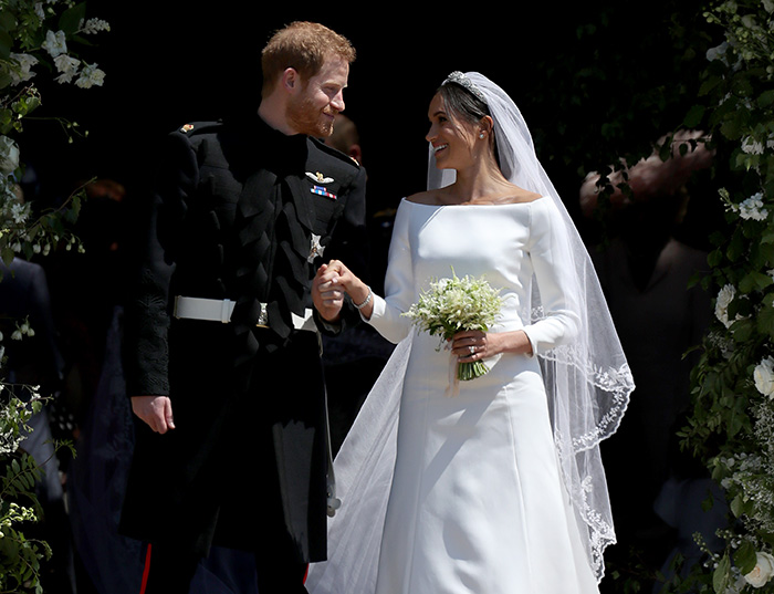 Prince Harry and Meghan Markle holding hands at their wedding, surrounded by floral decorations and guests. Prince Harry and Meghan Markle holding hands at their wedding, surrounded by floral decorations and guests.