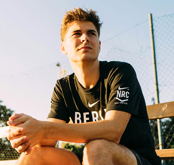 Young man in sportswear sitting outdoors on a bench, reflecting on moments involving huge risks with no logical reason.