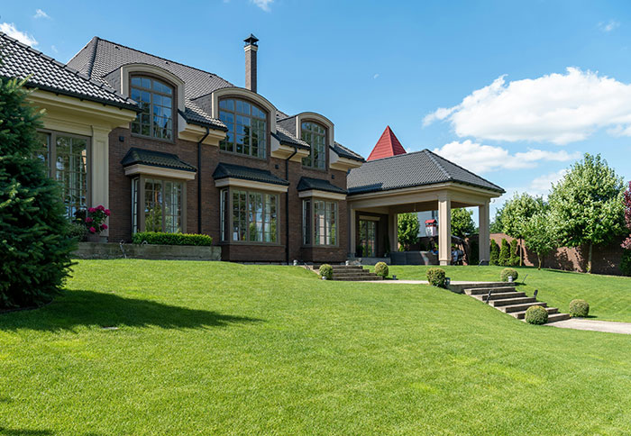 Large modern house with expansive lawn, illustrating huge risks taken for absolutely no logical reason outdoors.
