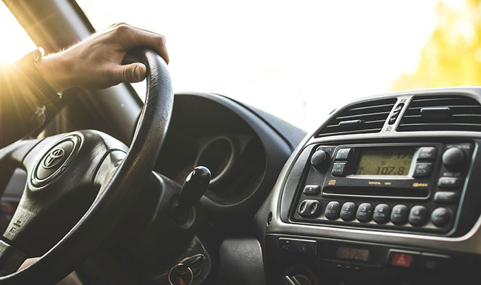 Driver gripping Toyota steering wheel inside car, illustrating huge risks taken with no logical reason at all.
