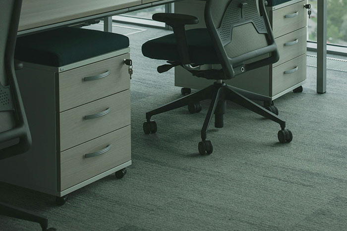 Office chairs and drawer units under a desk in a modern workspace, illustrating people taking huge risks.