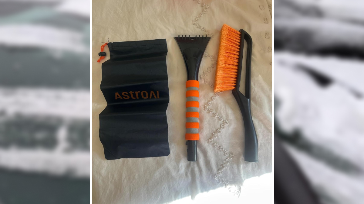 Car cleaning tools including ice scraper and brush with orange bristles laid out on a cloth surface for practical car advice.