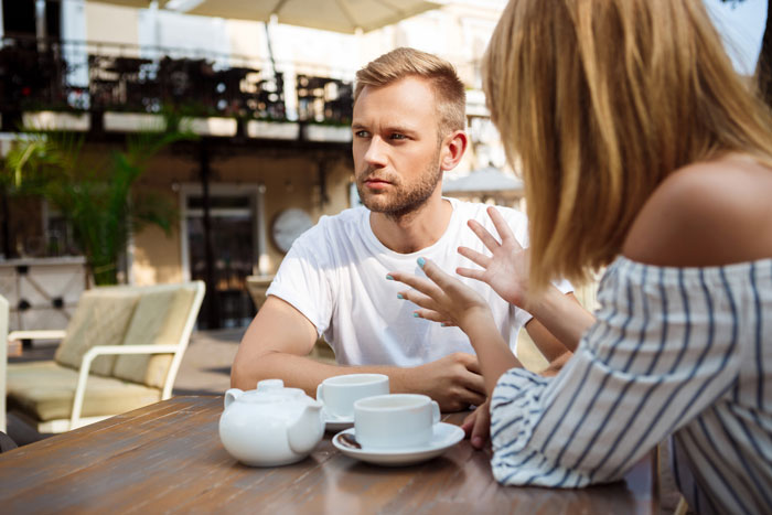 Couple having tense conversation at a café table after expensive meals order backfires on guy paying the bill. Couple having tense conversation at a café table after expensive meals order backfires on guy paying the bill.