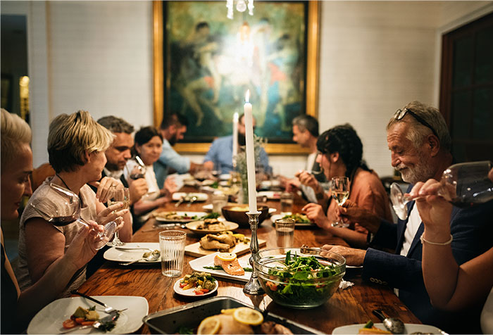Group of people dining together around a table with food and drinks, capturing a moment of treating the table at dinner. Group of people dining together around a table with food and drinks, capturing a moment of treating the table at dinner.