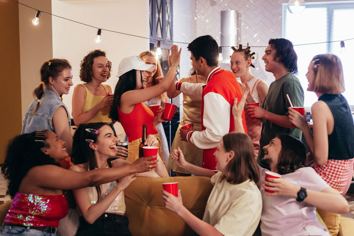 Group of students at a lively house party, sharing drinks and enjoying the roommate’s celebration together.
