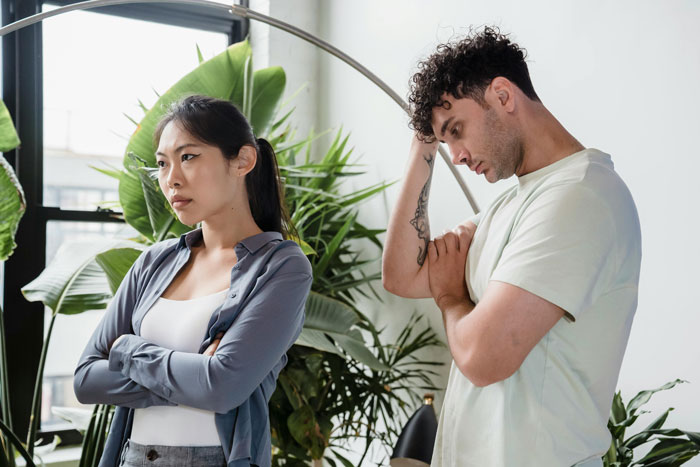 Two roommates in a tense conversation, one looking frustrated and the other unsure, reflecting discomfort during a party conflict.