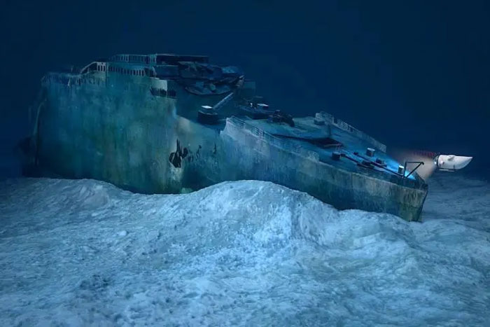 Sunken shipwreck on ocean floor illuminated by underwater lights, illustrating OceanGate implosion disaster investigation. Sunken shipwreck on ocean floor illuminated by underwater lights, illustrating OceanGate implosion disaster investigation.