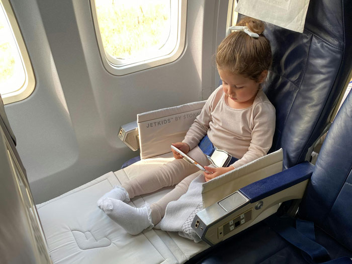 Young child with special needs sitting on airplane seat with leg rest during flight, passenger moves seats nearby after kickfest. Young child with special needs sitting on airplane seat with leg rest during flight, passenger moves seats nearby after kickfest.