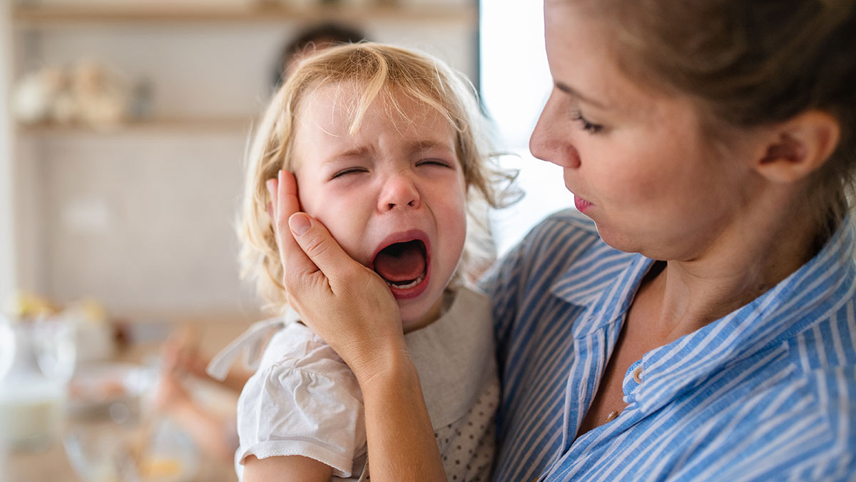 Woman comforting crying toddler indoors, illustrating roommate vanishes with ex and leaves guy with kid scenario.