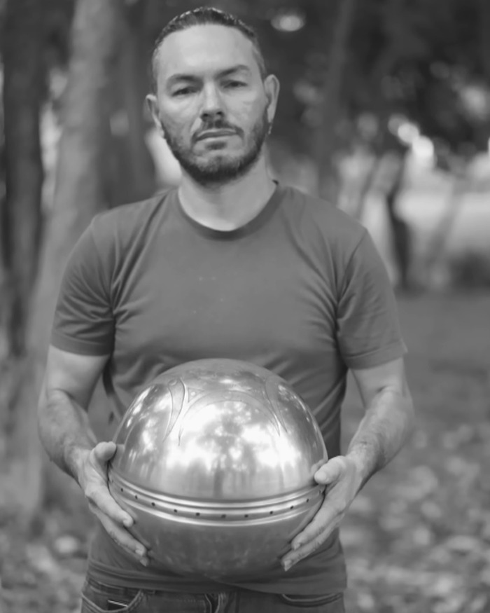 Man holding a metallic UFO with ominous inscriptions about origin of birth in an outdoor setting with trees in background Man holding a metallic UFO with ominous inscriptions about origin of birth in an outdoor setting with trees in background