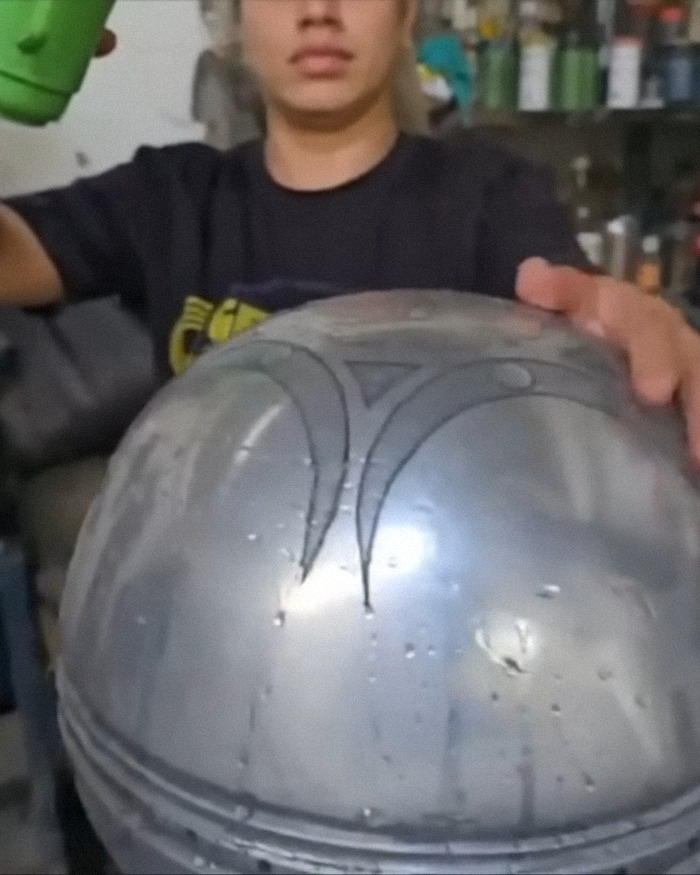 Person holding metallic UFO with ominous symbols about origin of birth in a workshop, scientists breaking silence on discovery. Person holding metallic UFO with ominous symbols about origin of birth in a workshop, scientists breaking silence on discovery.