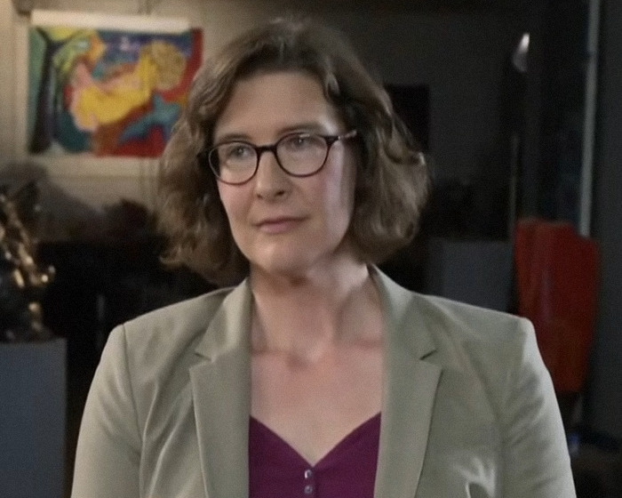 Scientist wearing glasses and blazer, discussing findings on UFO with writing about origin of birth in an indoor setting. Scientist wearing glasses and blazer, discussing findings on UFO with writing about origin of birth in an indoor setting.