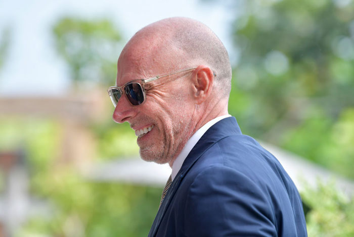 Scott Galloway smiling outdoors, wearing sunglasses and a suit, illustrating money rules behind net worth growth.