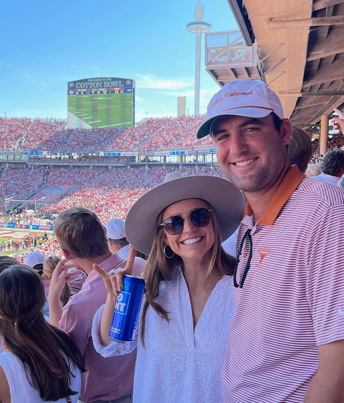 Scottie Scheffler and his wife enjoying a crowded Cotton Bowl stadium, highlighting Scottie Scheffler’s net worth and the financial power in golf.
