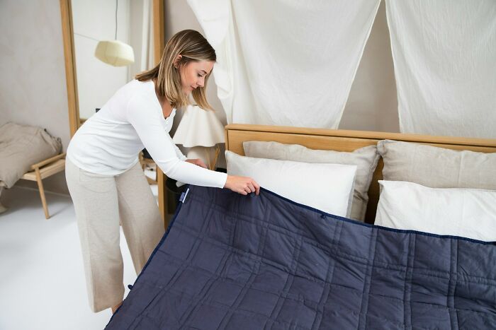 Woman making bed in a cozy bedroom, illustrating industry secrets about what they’re really like behind closed doors.