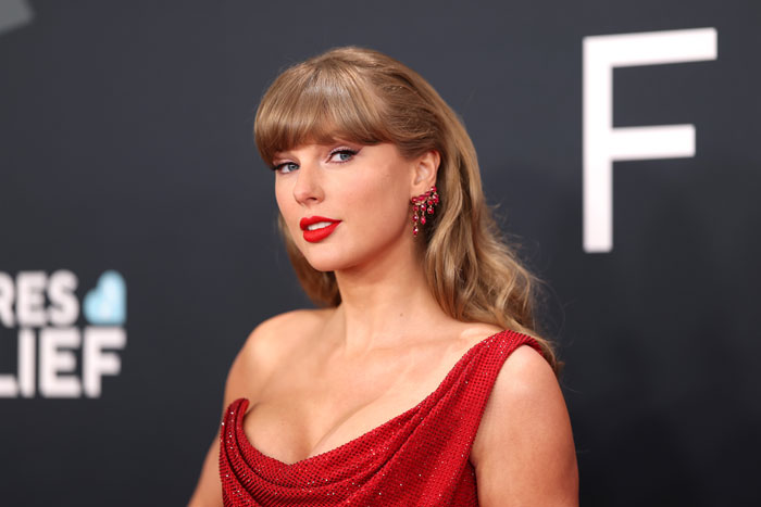 Taylor Swift in a red dress and earrings, posing on a black carpet event amid Trump claims about her image. Taylor Swift in a red dress and earrings, posing on a black carpet event amid Trump claims about her image.
