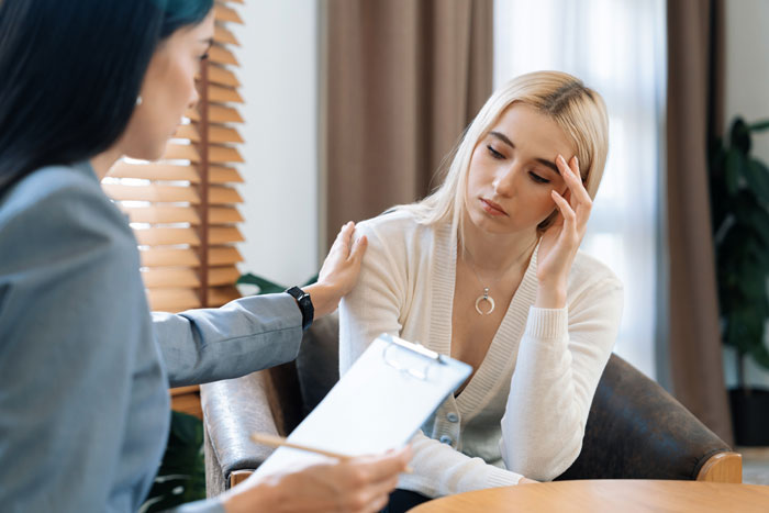 Couple seeking help with relationship struggles during a therapy session, woman looking upset while therapist offers support. Couple seeking help with relationship struggles during a therapy session, woman looking upset while therapist offers support.
