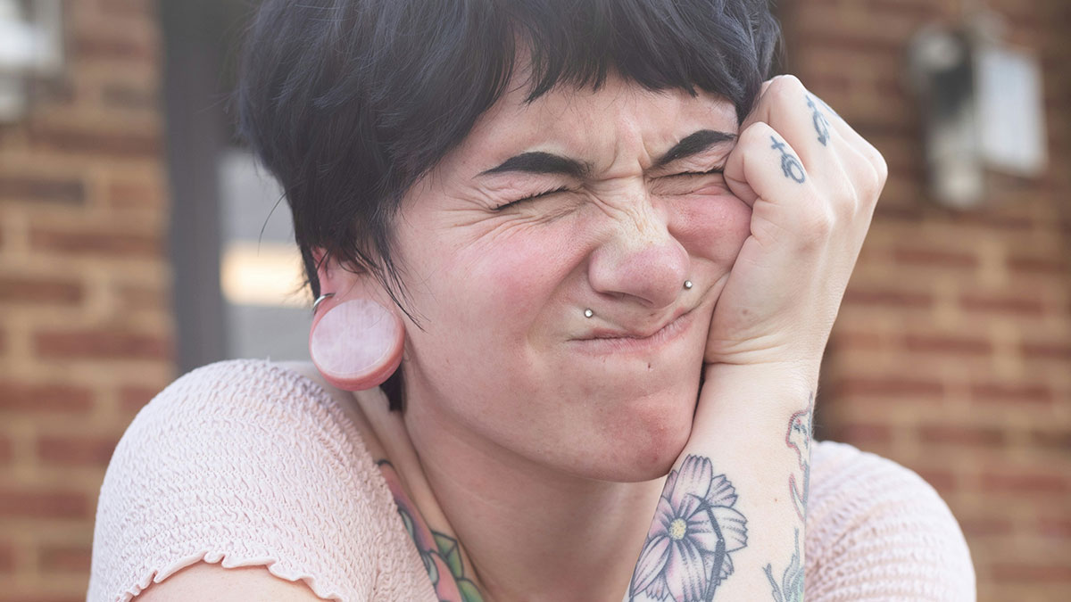 Person with face scrunched in distress showing tattoos and piercings, representing things that could destroy lives quickly.