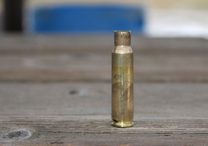 Single bullet casing standing upright on wooden surface symbolizing things that could destroy lives in seconds.
