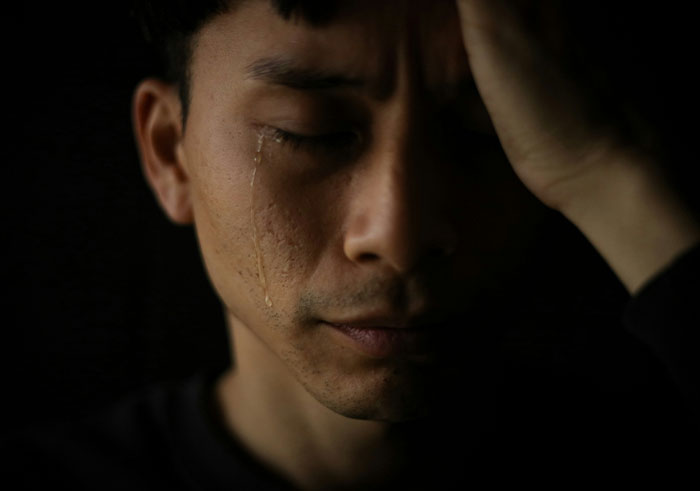Man with tear running down face, holding head in hand, illustrating emotional impact of things that destroy lives quickly.