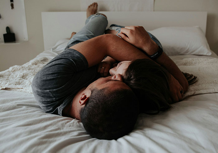 Couple lying closely on bed embracing each other, depicting moments that could completely destroy people’s lives in seconds.